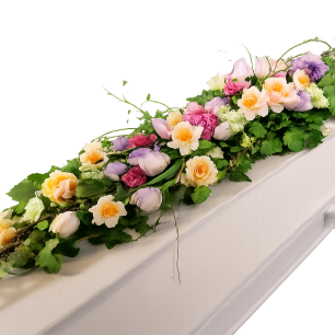 Kista dekorerad med en blomstergirlang av rosor i olika färger, inklusive gult, rosa och lila, omgiven av gröna blad.