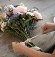 En bukett med blommor binds samman med ett band på ett bord.