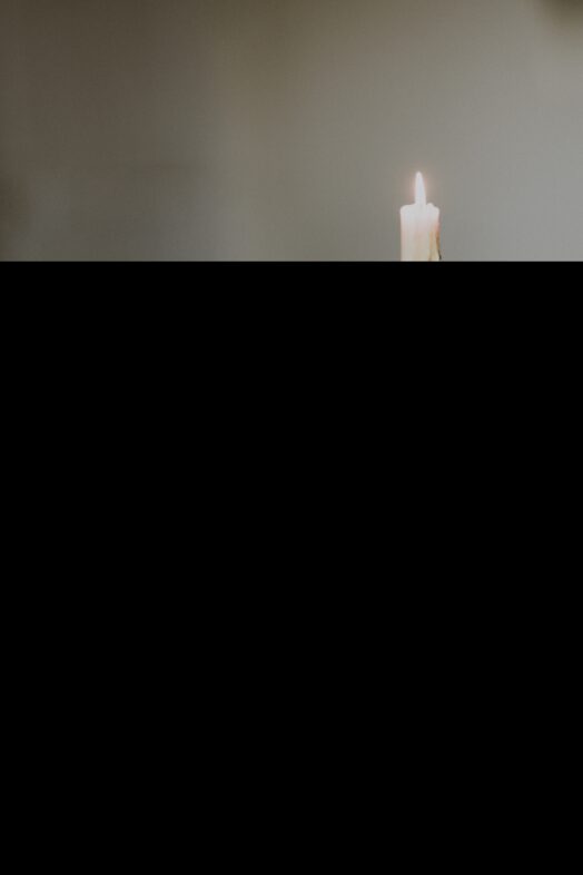 Ett tänt ljus står ensam mot en suddig bakgrund.